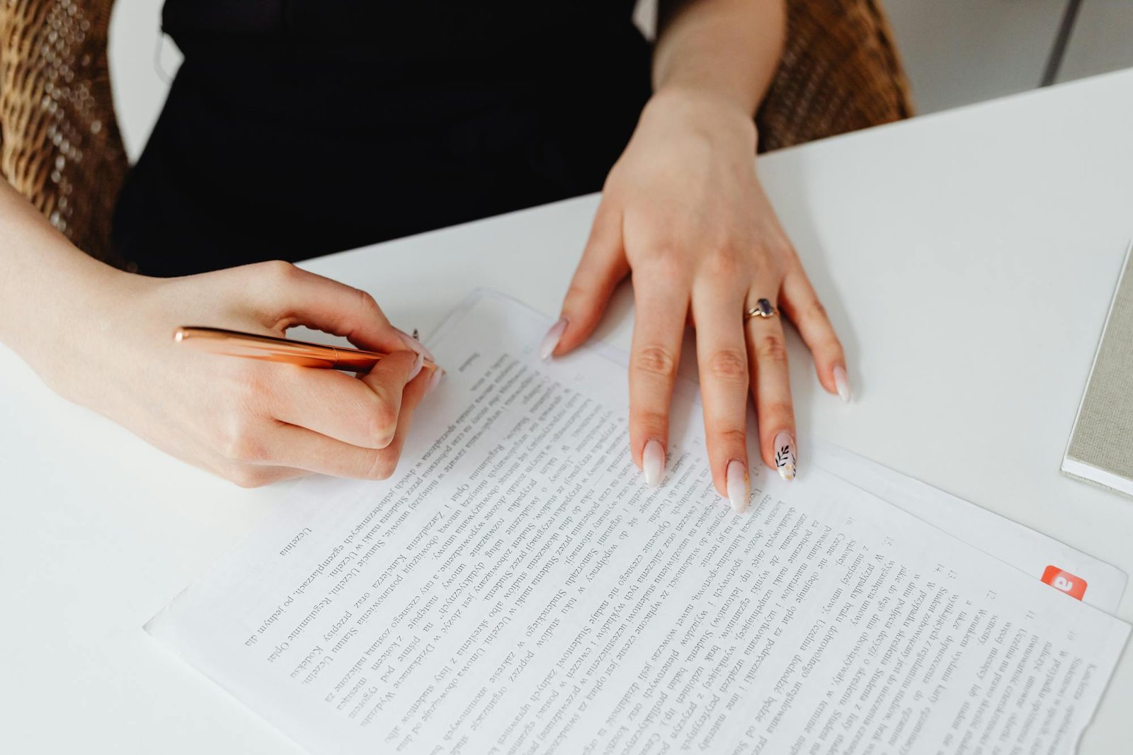 Person writing on a document with a pen